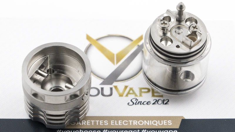 Le cap se retire comme celui d'un dripper. Il offre une chambre d'atomisation en dôme, de petite dimension. Les deux petits tubes sont les arrivées d'air sur le coil. En tant qu'amateurs de vape serrée, MTL ou RDL, vous connaissez l'importance d'une arrivée d'air proche du coil. C'est cette configuration qui donne toute l'intensité que vous attendez de cette manière de vapoter. L'important n'est pas tant le volume de vapeur, que sa densité et son dynamisme.