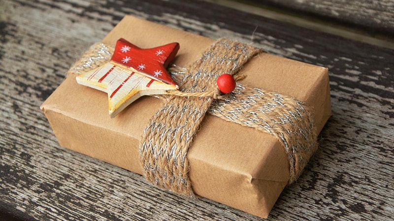 un cadeau emballé en papier Craft avec comme décoration une étoile rouge en bois