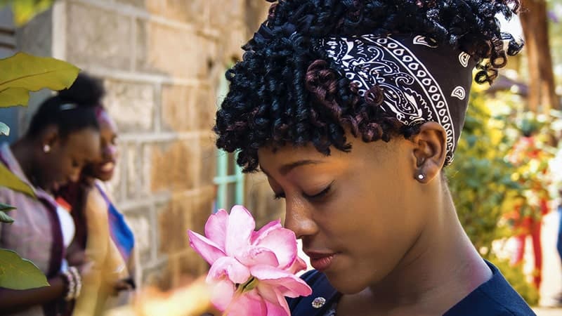 Une femme ayant les yeux fermés prend du plaisir à sentir une fleur rose